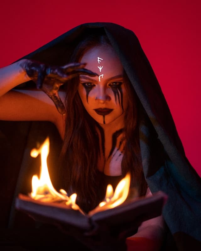 A photo of a witch conducting a ritual over a burning book.